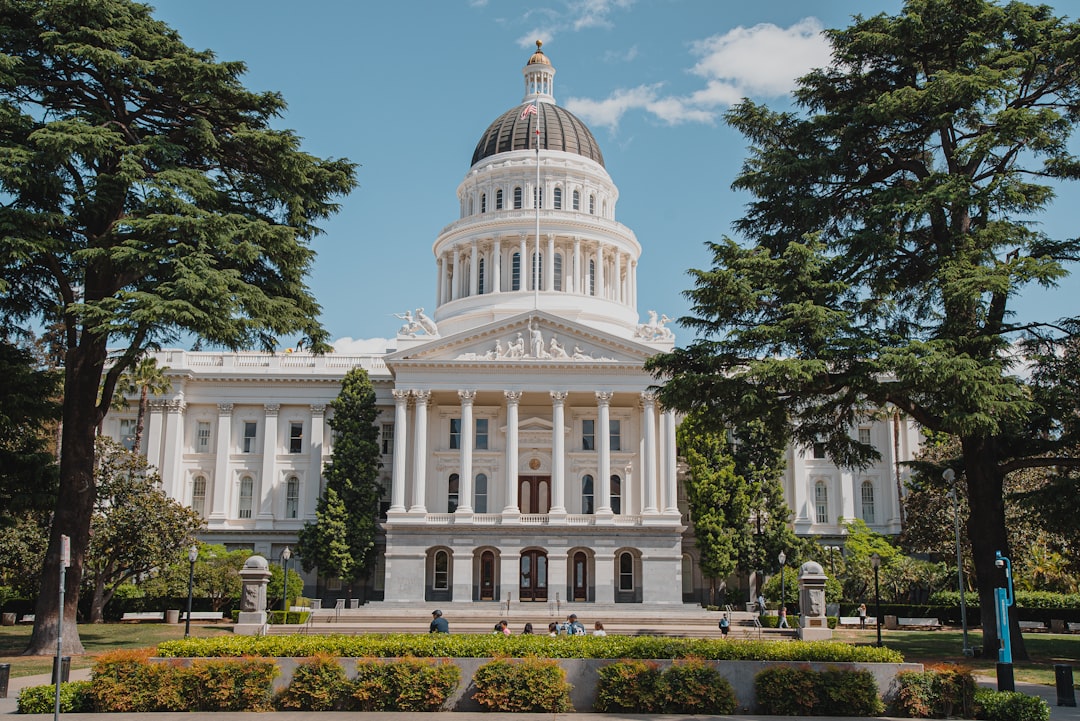 カリフォルニア州議事堂とAI規制の象徴的イメージ。税とプライバシーと公共調達の圧力